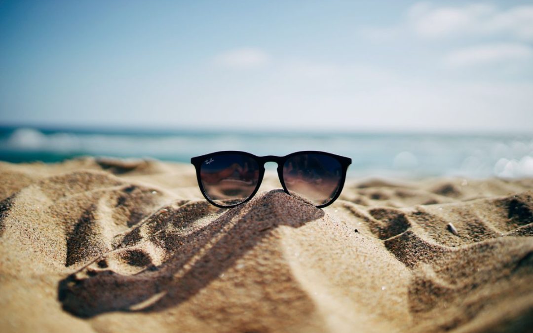 A pair of sunglasses sitting in the sand at the beach